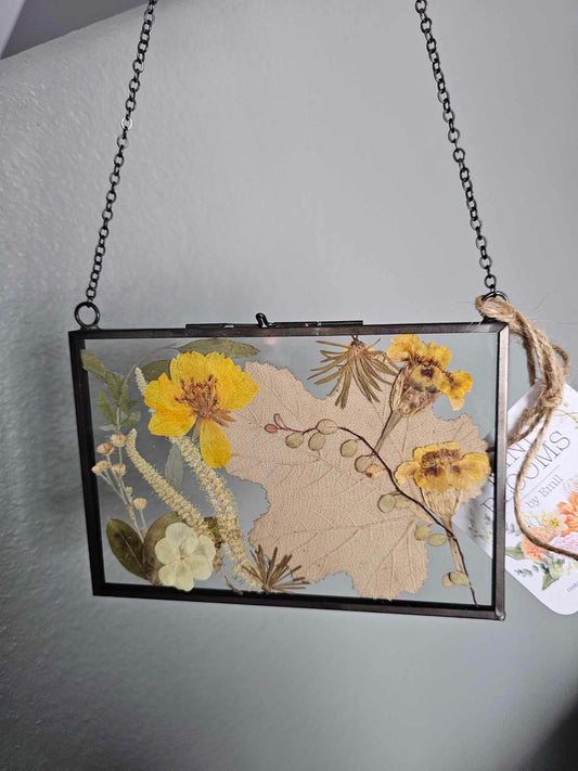 Vintage style black frame with pressed tan, natural and yellow flowers and leaves